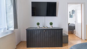 A room with a dark wooden cabinet, a flat-screen TV mounted above it, and a small potted plant on top.