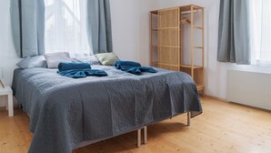 A bedroom with a bed, a wooden wardrobe, and a window with curtains.
