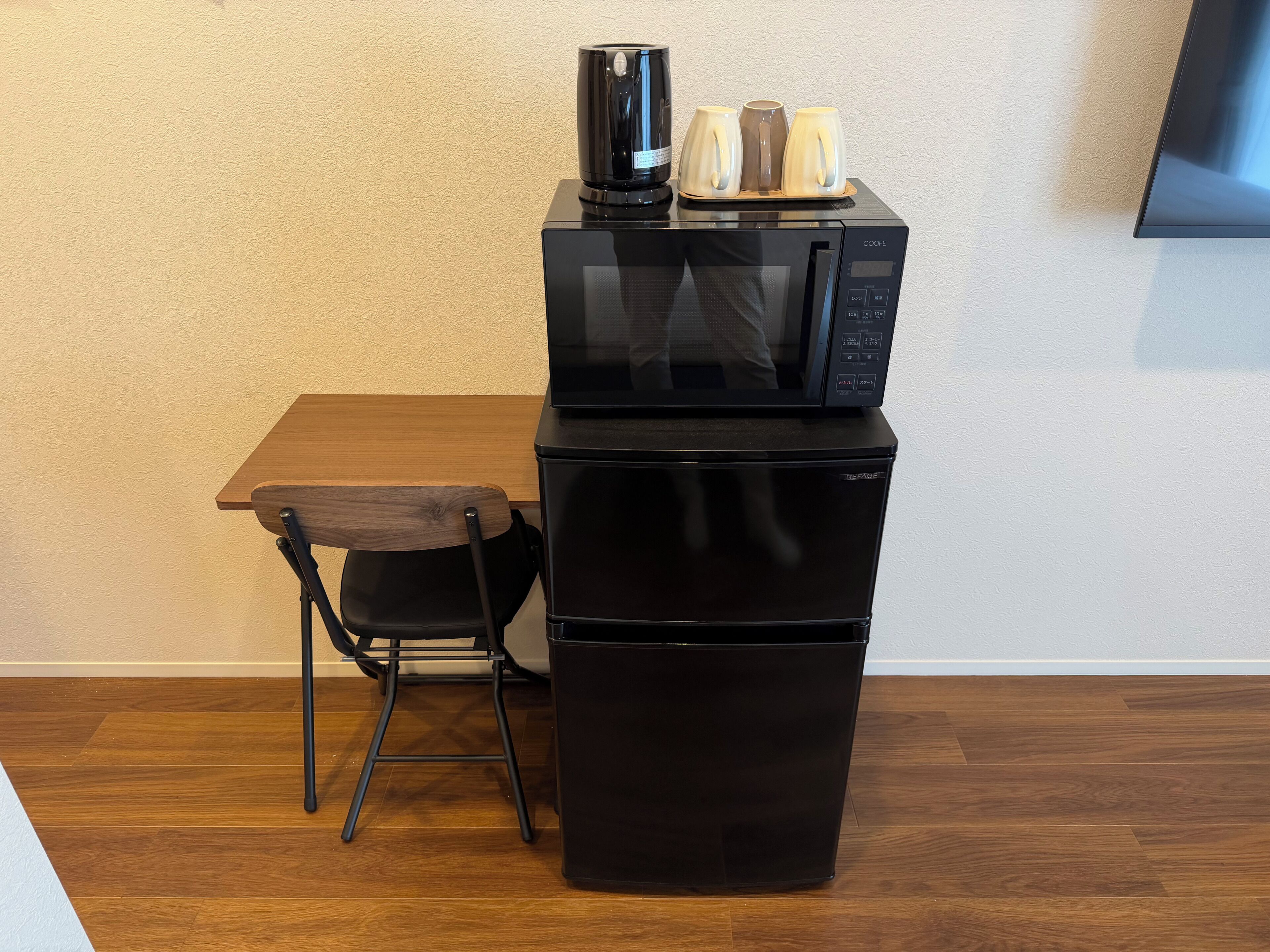 A compact kitchenette with a microwave, a small refrigerator, and a coffee maker on a table.