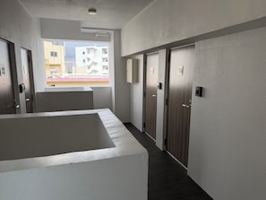 A hallway with a large window, a door with a lock, and a wall-mounted light fixture. - Hotel Living Inn Asahibashiekimae EAST (Naha)