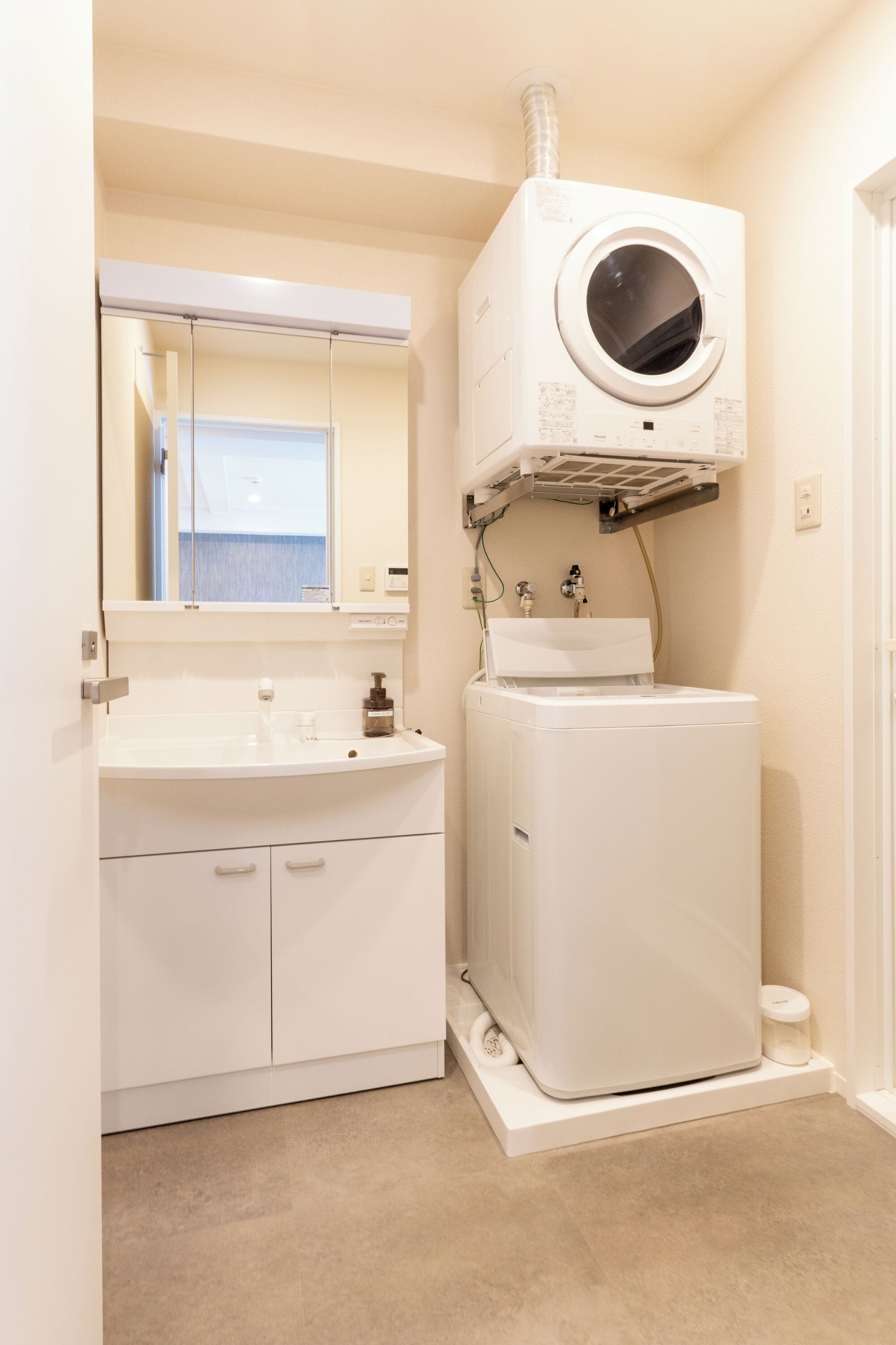 A compact bathroom with a sink, mirror, and a white washing machine.