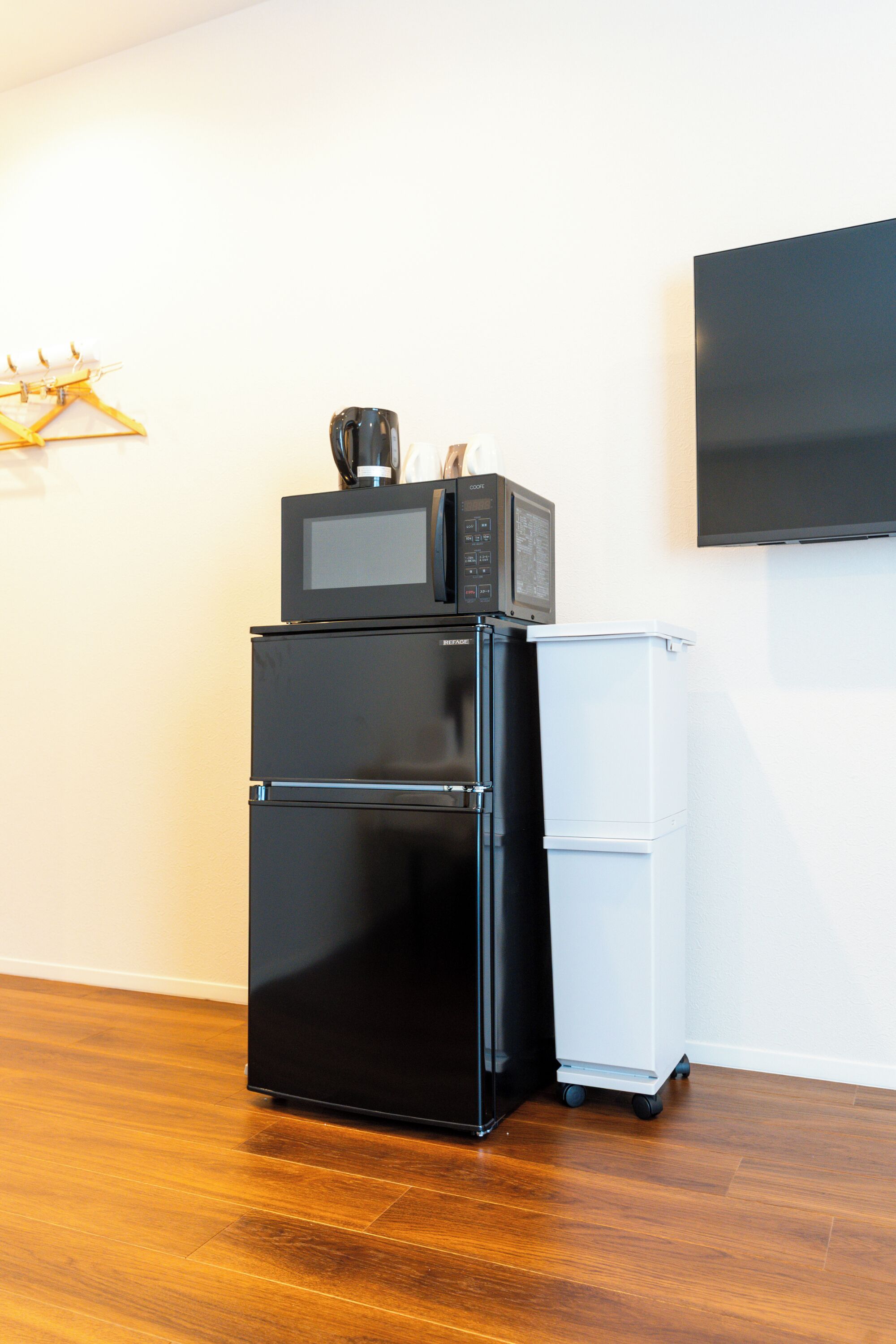 A compact kitchenette with a black refrigerator, a microwave, and a small white cabinet.