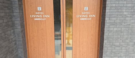 Eine Holztür mit doppeltem Flügel, mit der Beschilderung 'HOTEL LIVING INN' und einem 'R'-Symbol.