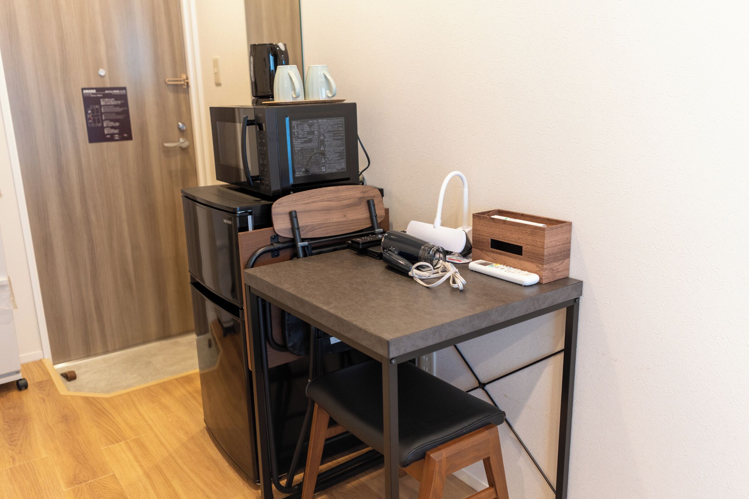 Una kitchenette compacta equipada con refrigerador, microondas y cafetera.