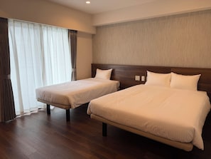 A hotel room with two beds, a wooden headboard, a large window with curtains, and a wooden floor. - Hotel Living Inn Asahibashiekimae EAST (Naha)
