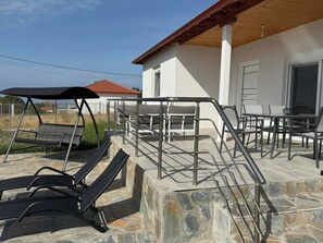 Eine Terrasse mit Gartenmöbeln, einer Schaukel und einer Steinmauer.