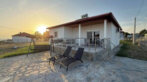 Une maison dotée d’un patio, d’un sol en pierre et offrant une vue sur le coucher de soleil.