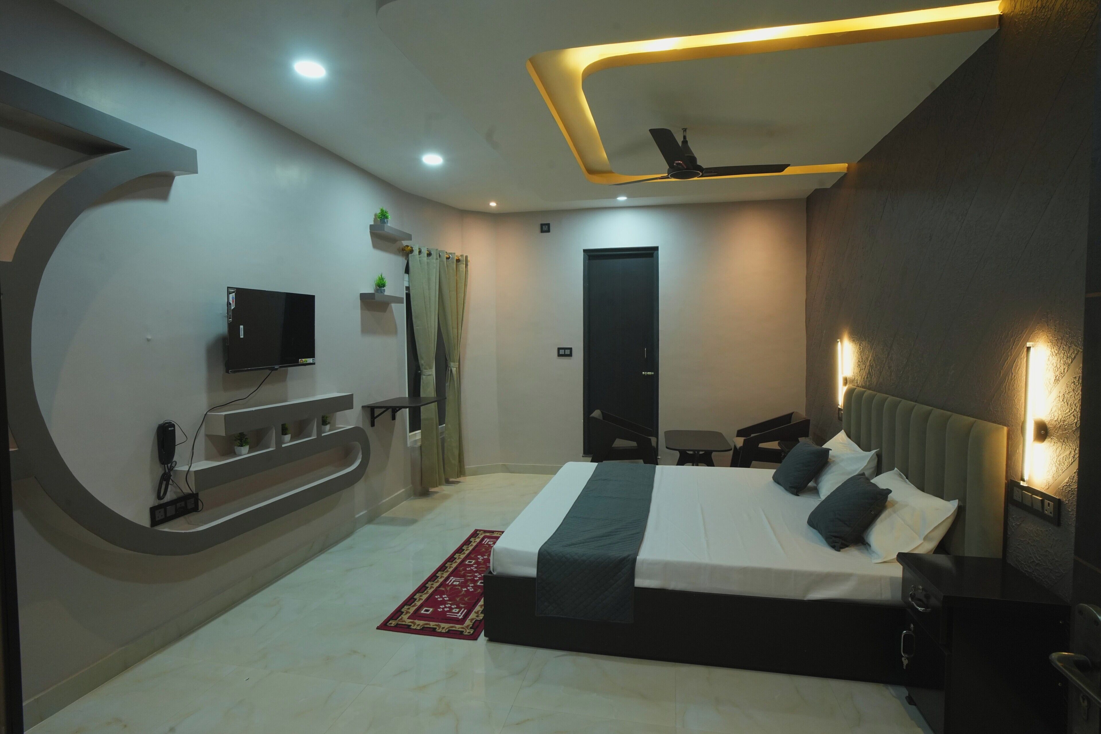 A modern bedroom with a bed, bedside tables, a TV, and a ceiling fan.
