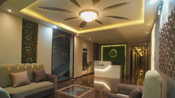 A modern lobby with a reception desk, sofas, a coffee table, and a staircase. - Kasa Courtyard (Begusarai)
