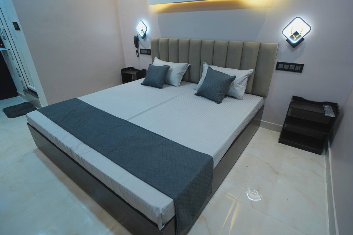 Un dormitorio moderno con una cama grande, mesitas de noche e iluminación en la pared.