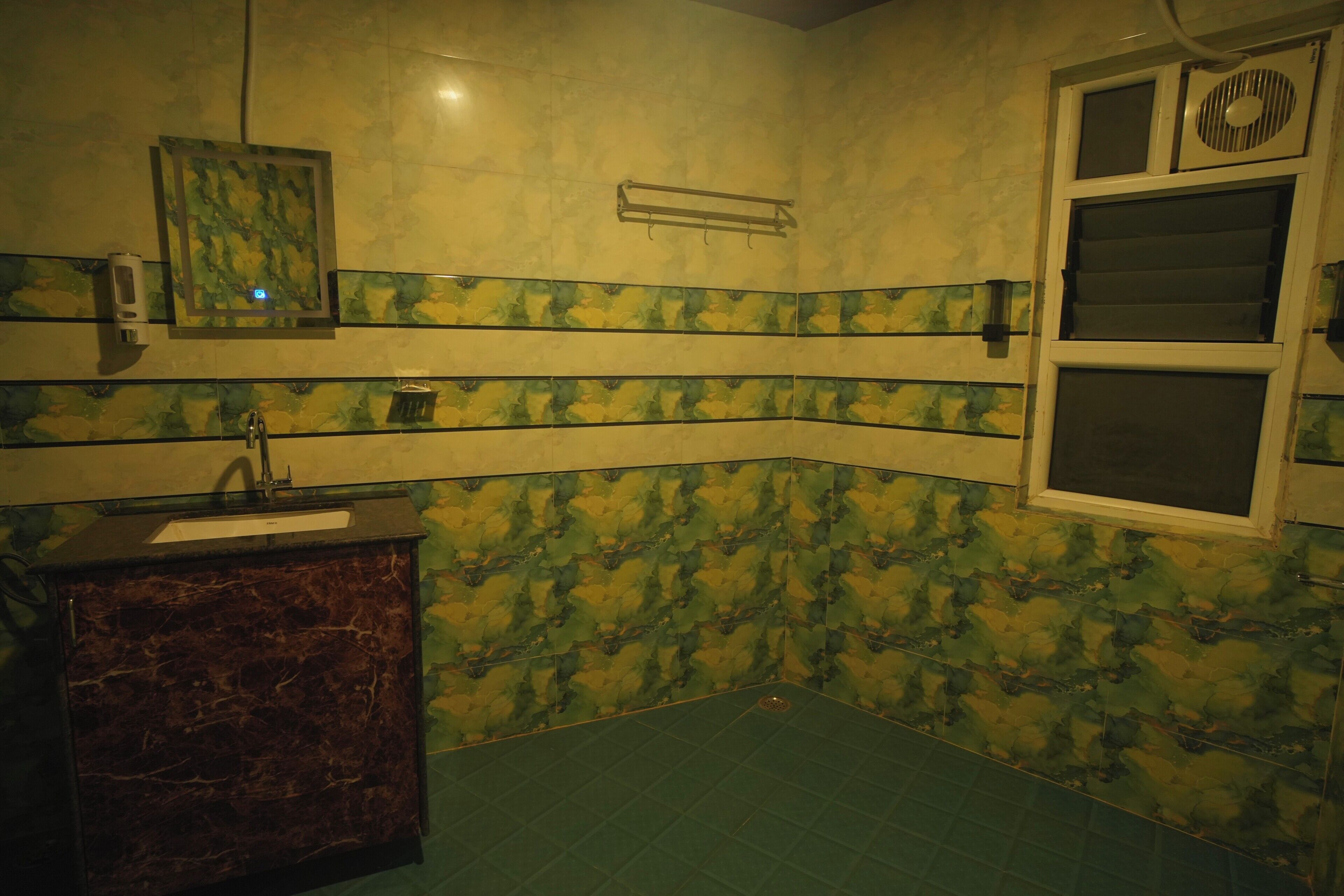 Un baño con lavamanos de mármol, un espejo y una ventana con ventilador.