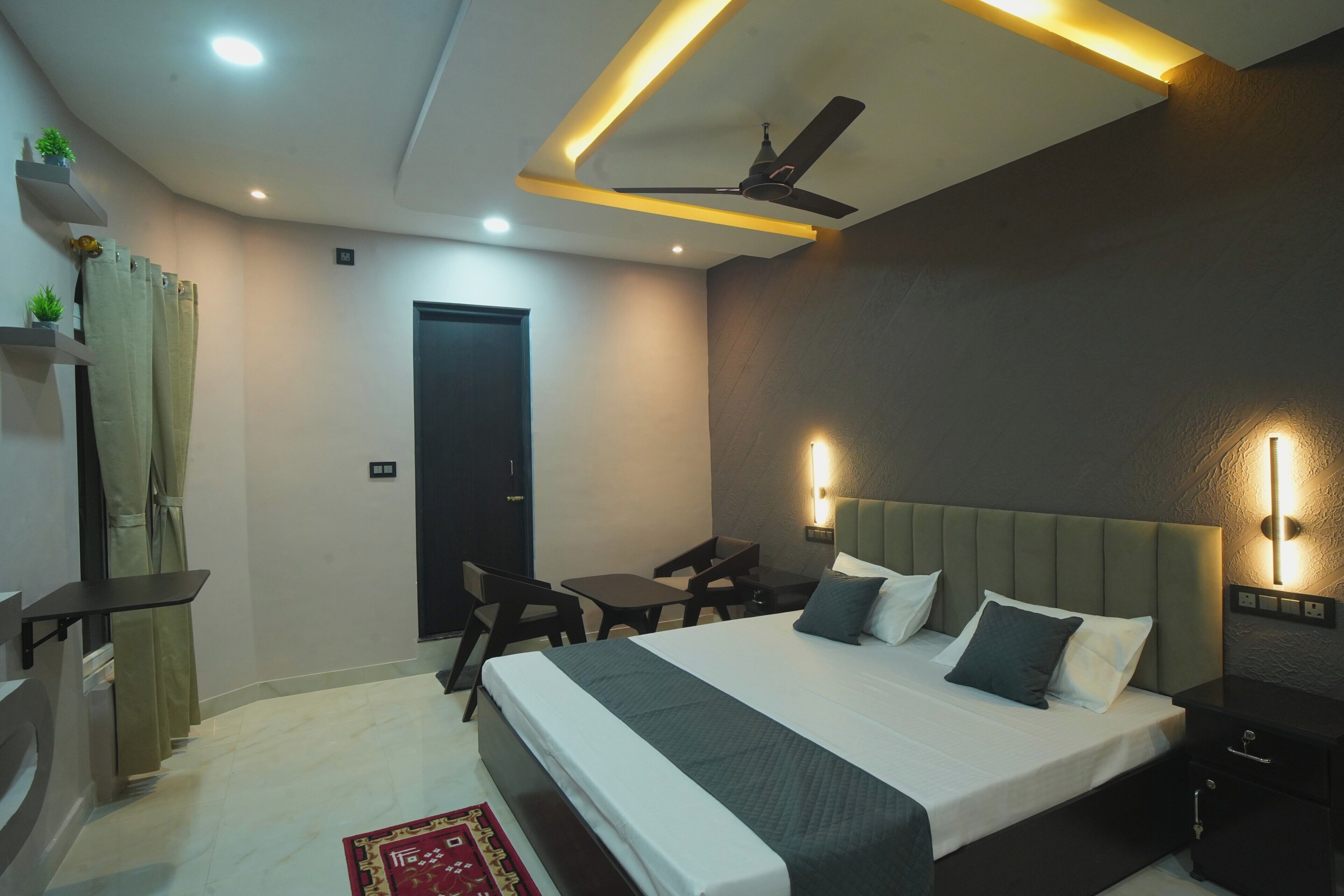 A modern hotel room with a bed, bedside tables, a desk, and a ceiling fan.