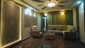 A modern lobby with a sofa, chairs, a coffee table, a decorative wall, and a ceiling with a light fixture. - Kasa Courtyard (Begusarai)