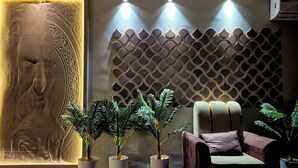 A room with a sculptural wall, a patterned wall, and a modern chair. - Kasa Courtyard (Begusarai)
