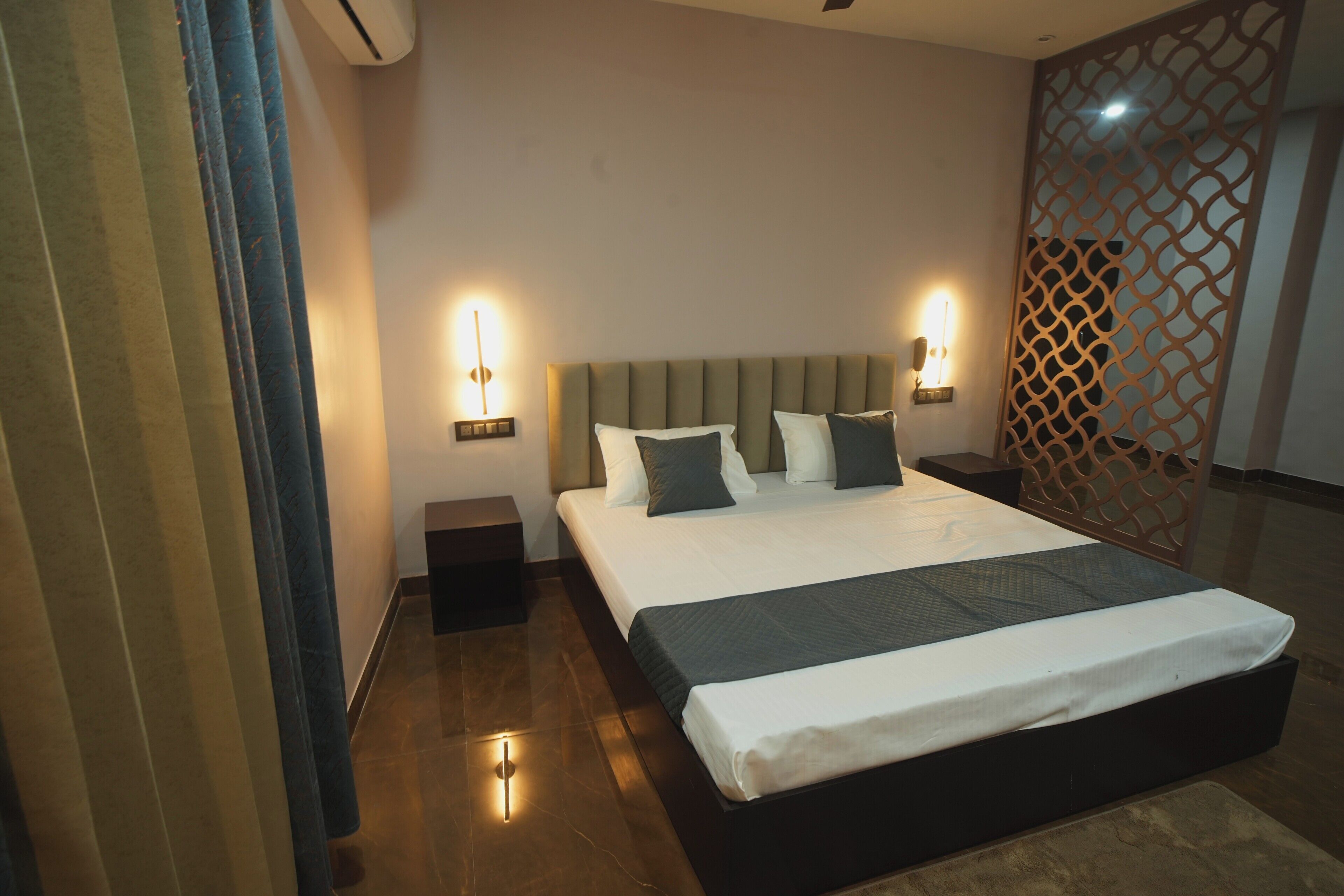 Ein modernes Hotelzimmer mit einem großen Bett, Nachttischlampen, einem Zierbildschirm und einem Nachttisch.