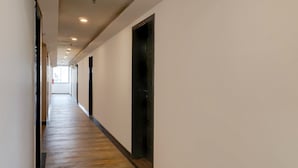 Un pasillo largo y estrecho con suelo de madera y paredes blancas, que conduce a una puerta al final.