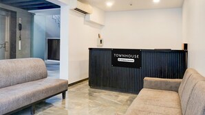 Un área de recepción con un letrero que dice 'Townhouse', un mostrador de recepción y dos sofás.
