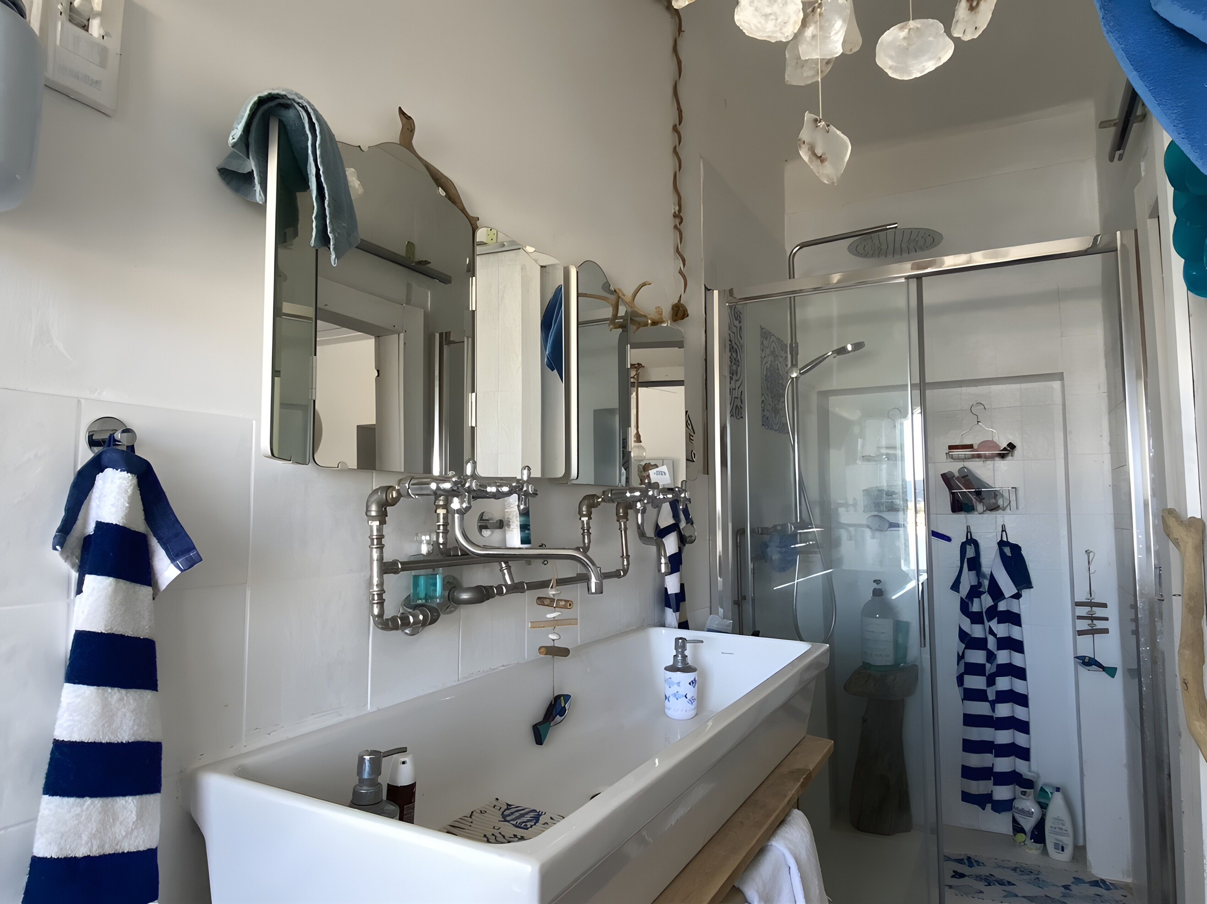 A bathroom with a white sink, a mirror, a shower, and a towel rack.