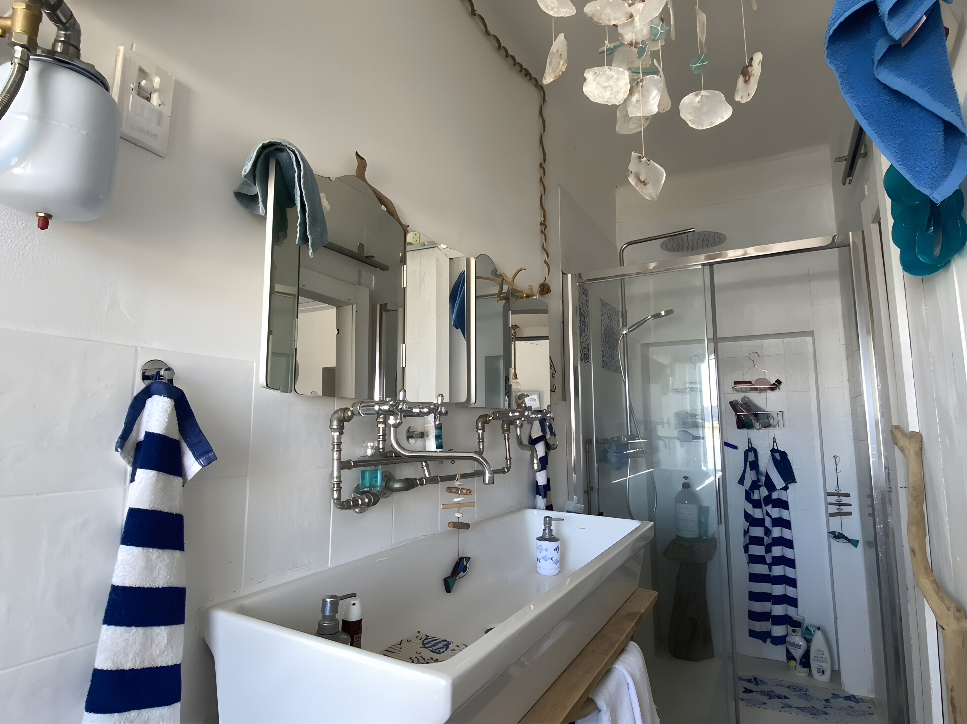 Een badkamer met een wit wastafel, een spiegel, een douche en een handdoekhouder.