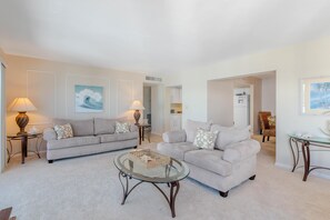 Ein Wohnzimmer mit zwei Sofas, einem Glastisch und einer Lampe.