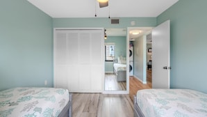 A bedroom with two beds, a closet, and a view into another room. - Bac Bay #223 (Fort Myers Beach)