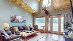 Un amplio salón con un ventanal grande, una cabeza de ciervo montada y una chimenea acogedora.
