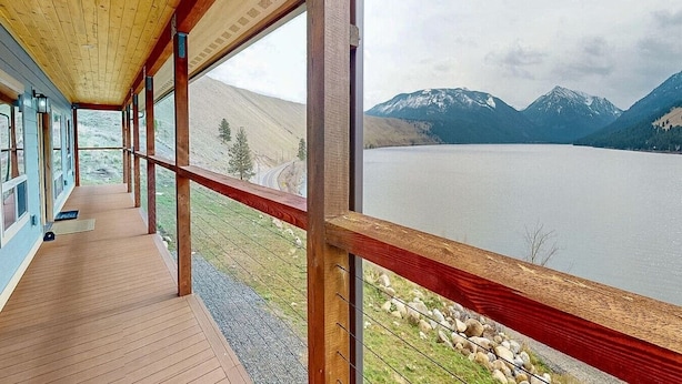Una terraza de madera con vistas a un lago y montañas.