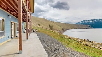 A building with a covered outdoor area, a gravel path, and a lake with mountains in the background.