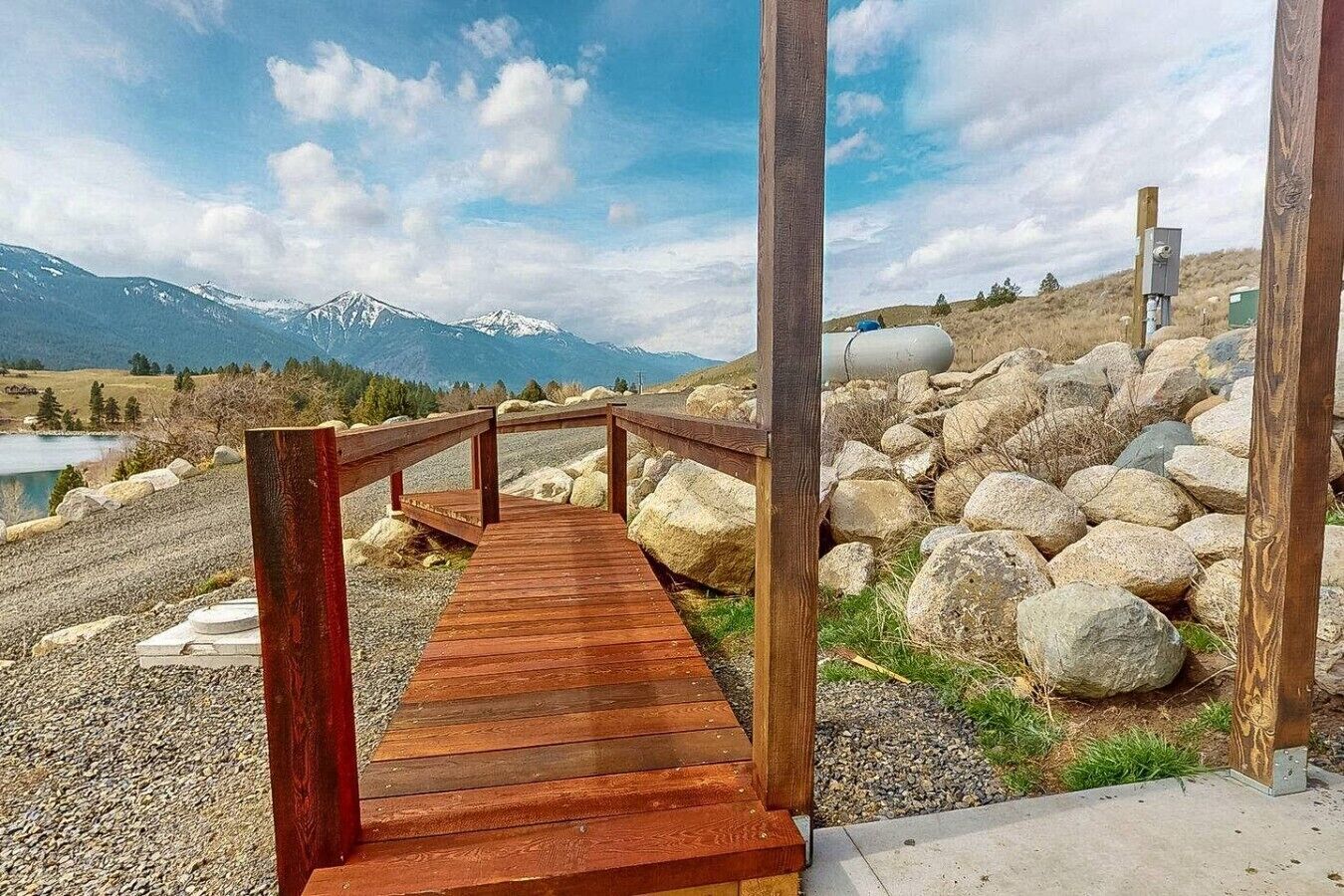 Un paseo marítimo de madera que conduce a una zona rocosa con una montaña al fondo.