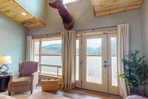A room with a large window, a chair, a lamp, a plant, and a mounted animal head. - 20 Moraine Tranquility Lodge  (upstairs unit) (Joseph)
