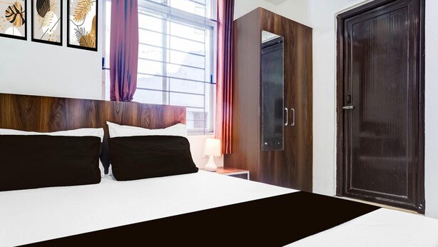 A hotel room with a large bed, a wooden headboard, a wardrobe, and a door. - Single Roomsixmile Guwahati (Guwahati)