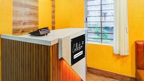 A reception desk with a sign, a window with a view, and a wooden wall. - Single Roomsixmile Guwahati (Guwahati)