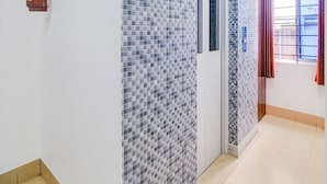 A hallway with tiled walls, a fire extinguisher, a door, and a window with curtains. - Single Roomsixmile Guwahati (Guwahati)