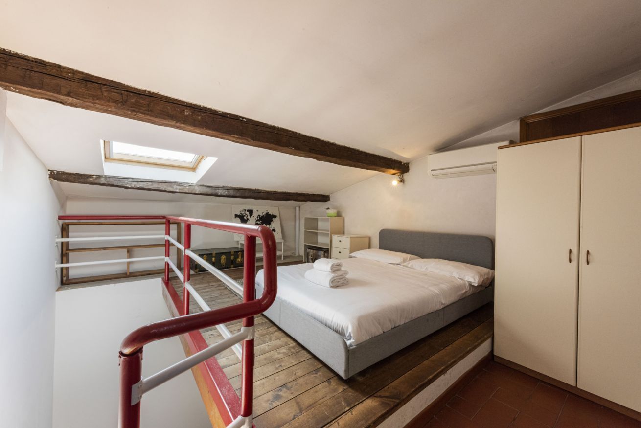 A bedroom with a bed, a wardrobe, a skylight, and a staircase.