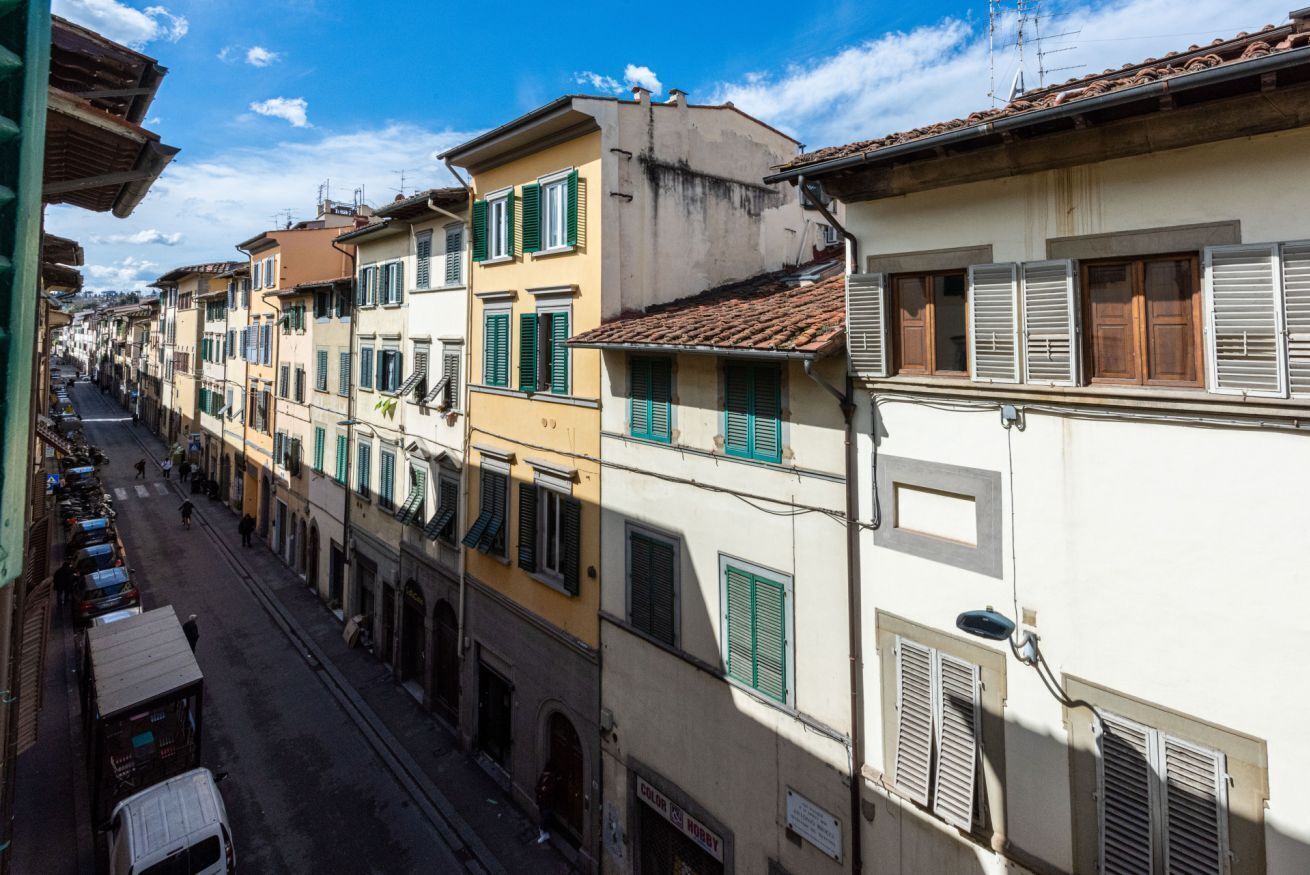 Eine schmale Straße, gesäumt von mehrstöckigen Gebäuden mit unterschiedlichen Architekturstilen und abweichenden Fenstergestaltungen.