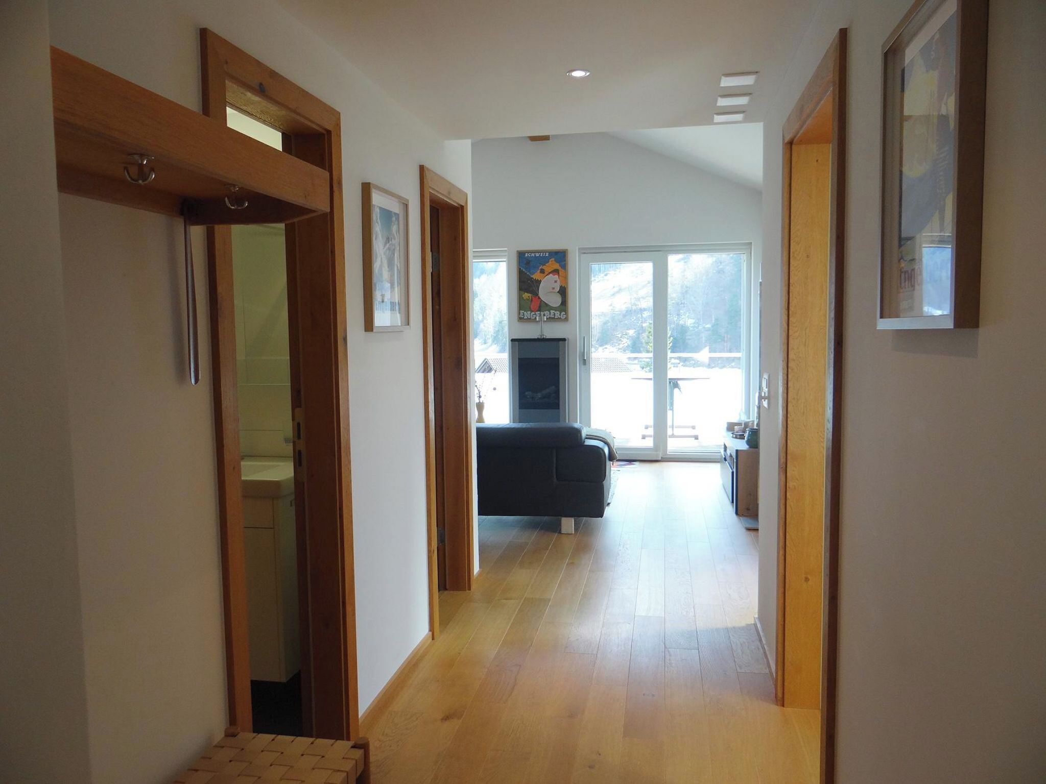 Un couloir avec un plancher en bois, un canapé et un téléviseur à l’arrière-plan.