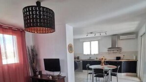 Una sala de estar con televisor, un comedor con mesa y sillas, y una cocina al fondo.