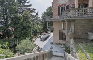 A courtyard with a dining area, a stone balustrade, and a building with patterned walls.