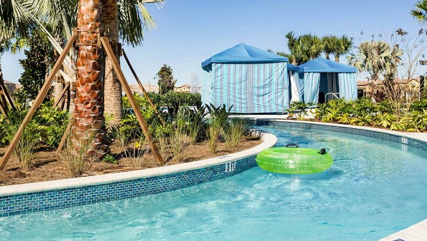 Ein Swimmingpool mit einer Palme, einem grünen Luftring und zwei blauen Zelten.