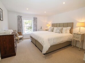 A bedroom with a bed, bedside tables, a dresser, a window with curtains, and a lamp. - 19 Queen Street (Emsworth)