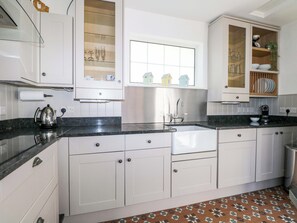 A modern kitchen with white cabinets, a stainless steel sink, and a window above the countertop. - 19 Queen Street (Emsworth)