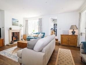A living room with a fireplace, sofa, coffee table, and wooden flooring. - 19 Queen Street (Emsworth)