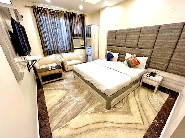 Una habitación de hotel moderna con una cama grande, un sofá, un televisor y una mesita de noche.