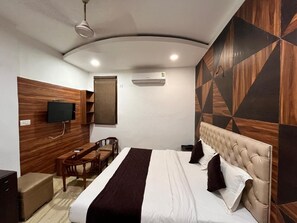 Ein Hotelzimmer mit einem Bett, einem Fernseher, einem Schreibtisch und einem Sessel.