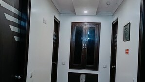 A hallway with a brown carpet, white walls, and two doors on either side. - Hotel Amrit Villa Karol Bagh New Delhi (New Delhi)