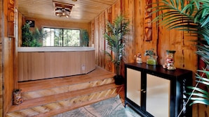 A wooden interior with a bench, a staircase, a console table with decorative items, and a large plant. - Hot Tub Cabin w/ Game Loft, Fireplace + Deck – Near Lake & Slopes (Big Bear Lake)