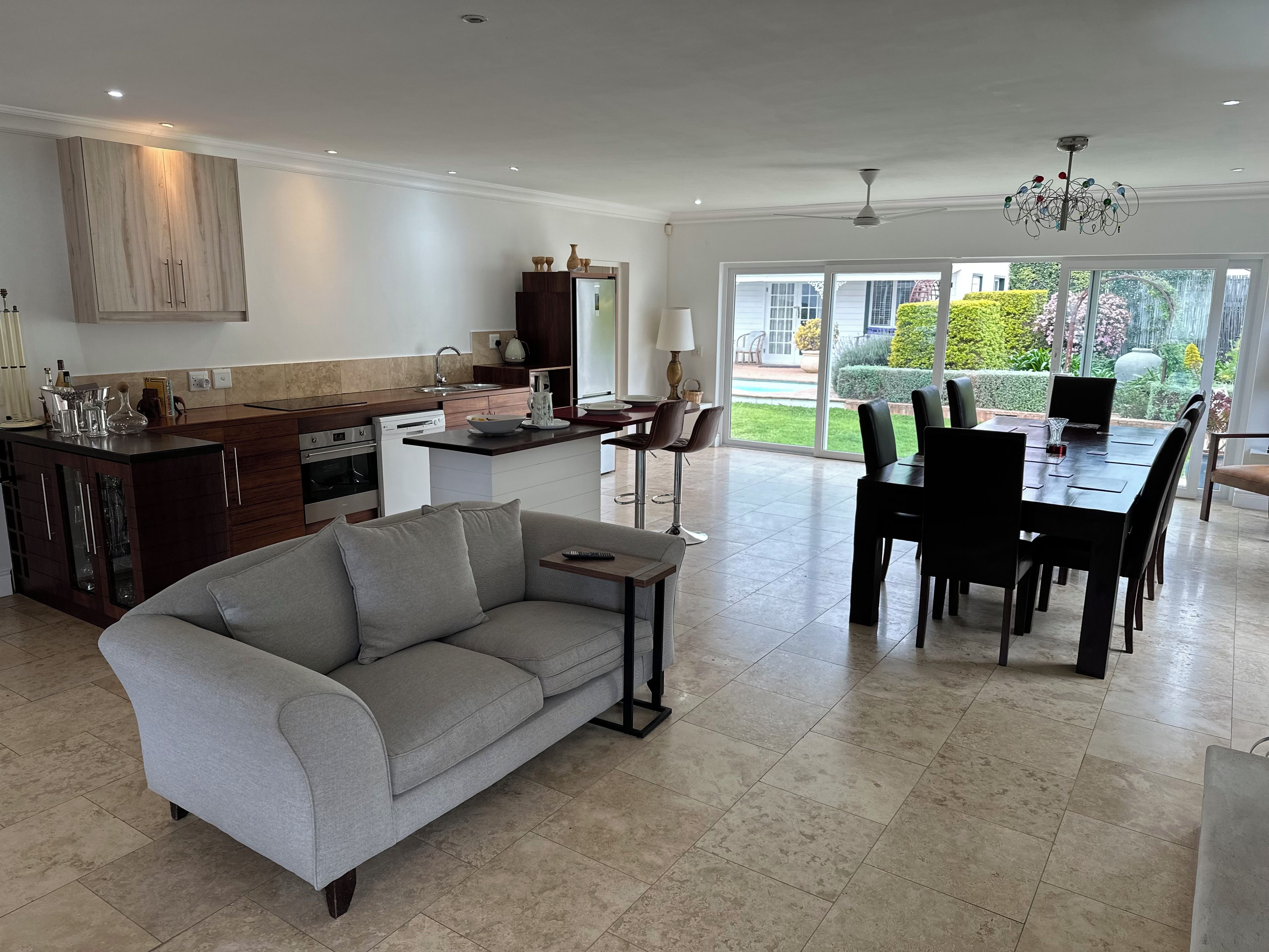 A modern kitchen with a dining area, a sofa, and a chandelier.