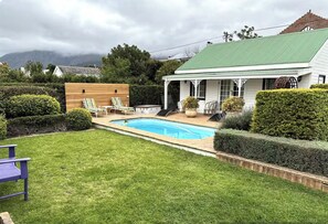 Una propiedad residencial con piscina, patio cubierto y césped cuidado.