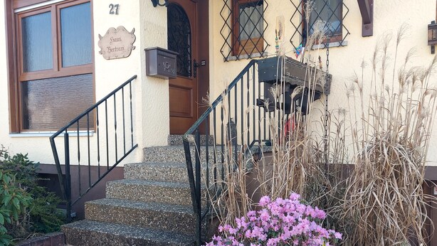 A building with a wooden door, a mailbox, and a staircase leading to the entrance. - Cozy vacation apartment "Haus Bertram" in Leun. in a quiet rural location. (Leun)