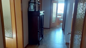 A hallway with wooden flooring, a dark wooden cabinet, and a door with frosted glass panels. - Cozy vacation apartment "Haus Bertram" in Leun. in a quiet rural location. (Leun)